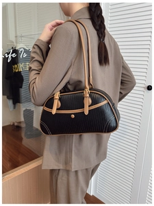 Detail view of the black woven shoulder bag with brown leather trim and golden buckle