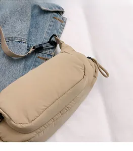 Close-up of khaki padded nylon crossbody bag with strap and black carabiner detail