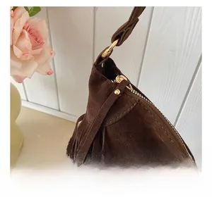 Détail de la fermeture éclair dorée et des franges en daim sur le sac bandoulière
