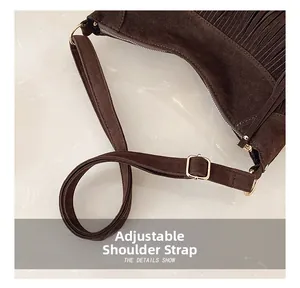 Détail de la bandoulière réglable sur sac en daim marron avec garniture dorée