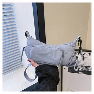 Detail view of a blue-grey nylon crescent bag with a rectangular front zipper pocket
