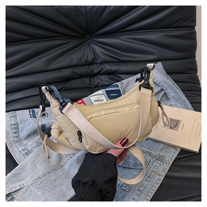 Detail of beige quilted nylon shoulder bag with wide strap and plastic buckle