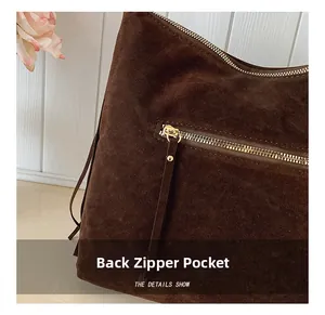 Détail de la poche zippée arrière sur un sac à bandoulière en daim marron et métal doré