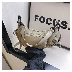 Detail view of khaki nylon crescent bag with multi-zipper pockets and utility strap