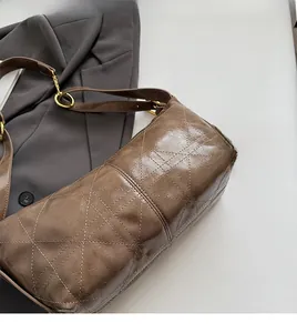 Close-up of caramel leather shoulder bag with geometric stitching and gold buckle detail