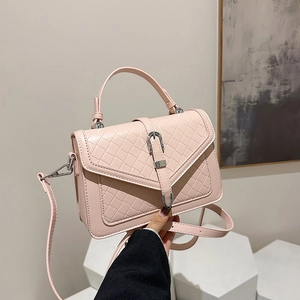 Sac bandoulière rose avec texture matelassée et boucle argentée tenu à la main