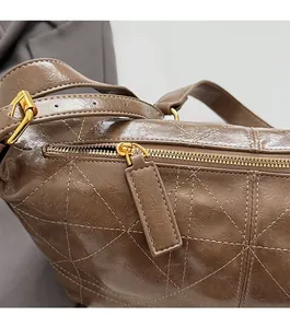 Detailed close-up of dark brown wax leather texture and golden zipper on shoulder bag