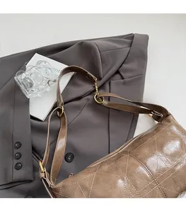 Detailed view of brown quilted crescent bag with white stitching and gold hardware