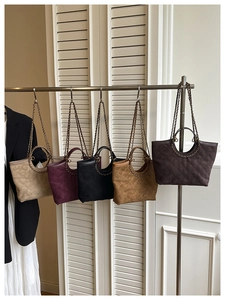 Quilted tote bags in various colors hanging on a rack with metal chain and round handles