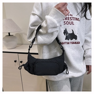 Model wearing a black wrinkled nylon shoulder bag with adjustable strap and side drawstring