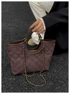 Detailed top view of a dark brown quilted tote bag with gold chain and leather handles