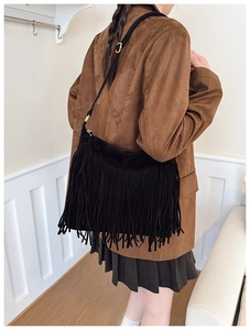 Detail of bohemian black suede bag showing long fringe tassels and golden metal buckle