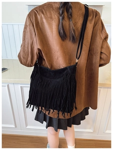 Détail d'un sac bandoulière en daim noir avec de longues franges élégantes