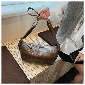 Detail of dark brown quilted leather bag featuring high-gloss oil wax finish and stitching