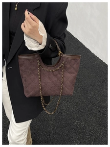 Detail of dark brown quilted suede tote bag with elegant gold chain shoulder strap