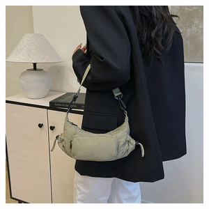Close-up of a light khaki nylon crescent bag with adjustable strap worn by a model
