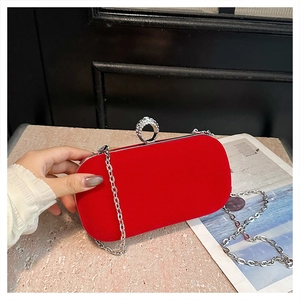 Detail of red velvet evening clutch featuring silver rhinestone ring clasp and metal chain