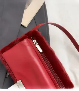 Détail du sac à bandoulière en cuir rouge avec bordure peluche et zip métallique