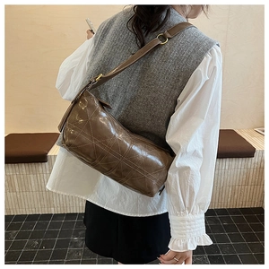 Detail of dark brown quilted crossbody bag with adjustable strap on model