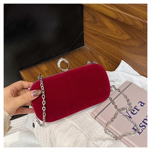 Close-up of red velvet evening clutch with sparkling rhinestone ring clasp and silver chain
