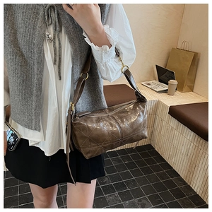 Detail of dark brown quilted leather shoulder bag with adjustable strap and gold metal hardware