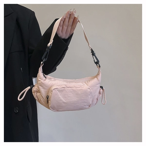 Detail of light pink crescent nylon crossbody bag featuring multi-pocket zipper design