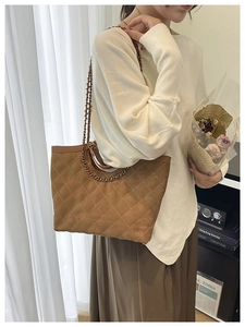 Detail of brown quilted tote bag with metal chain strap and suede texture finish