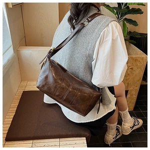 Detail of dark brown quilted crossbody bag with adjustable wide strap and gold hardware