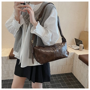 Detail of dark brown quilted shoulder bag showing glossy texture and adjustable strap