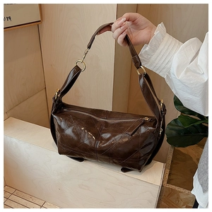 Detail of dark brown quilted crossbody bag with gold zipper and glossy leather texture
