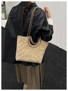 Chic beige quilted tote bag with metal chain straps worn by a model in a minimalist setting