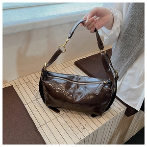 Detail of dark brown quilted shoulder bag with glossy finish and gold metal hardware