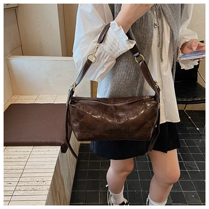 Detail of dark brown quilted leather crossbody bag with adjustable strap and gold hardware