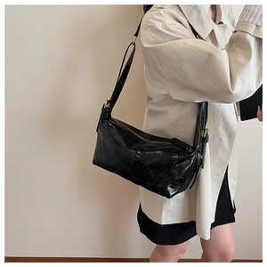 Detail of black glossy leather shoulder bag featuring 3D geometric quilted pattern
