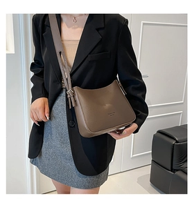 Détail d'un sac bandoulière marron porté par un mannequin en costume professionnel
