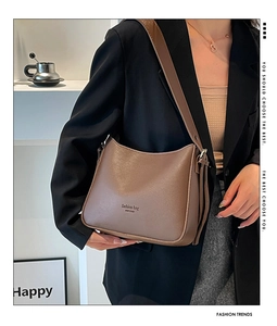 Détail du sac en cuir marron foncé avec texte mode et large bandoulière sur mannequin