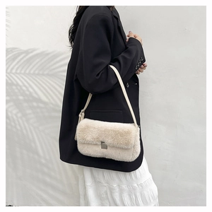 Détail du sac à épaule en fausse fourrure crème avec boucle argentée porté par le mannequin