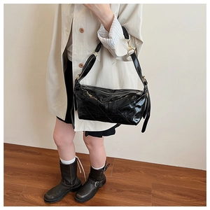 Detail of black glossy crossbody bag with geometric stitching and gold metal buckles