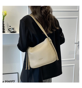 Sac bandoulière vintage crème porté avec blazer noir dans un décor intérieur