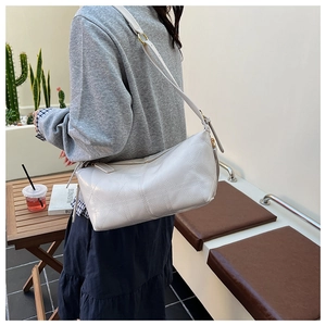 Close-up of quilted geometric pattern and golden ring hardware on light gray crossbody bag