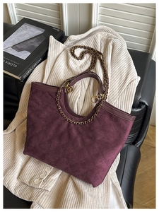 Dettaglio della borsa tote viola trapuntata con tracolla a catena su maglia morbida