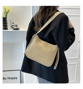 Détail du sac bandoulière beige en simili cuir avec pompon et lettrage de mode