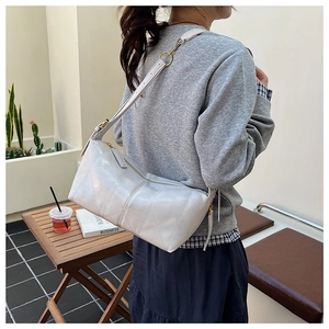 Detail of white quilted crossbody bag with star pattern in an outdoor cafe setting