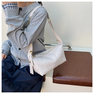 Detail of off-white quilted crossbody bag with adjustable strap and golden hardware