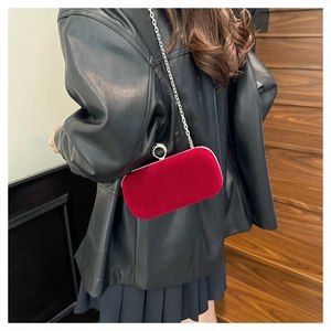 Model showing a deep red velvet evening clutch bag with a diamond-set ring handle