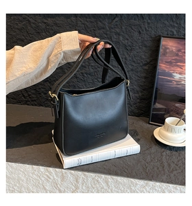 Détail du sac à bandoulière en cuir noir mat avec boucle dorée et logo embossé