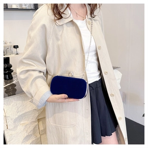 Detail of dark blue velvet evening bag with rhinestone clasp and metal chain strap