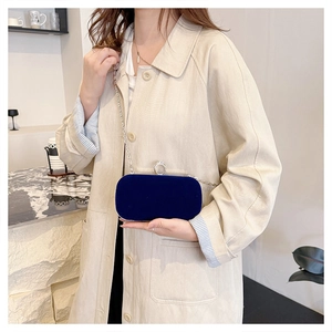Detail of a dark blue velvet evening clutch bag with round rhinestone clasp and silver chain