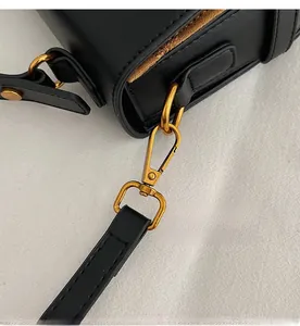Detailaufnahme der hochwertigen goldenen Metallhaken an der schwarzen Ledertasche