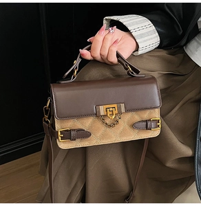 Detail der zweifarbigen Tasche mit goldener Schließe und strukturierter Oberfläche